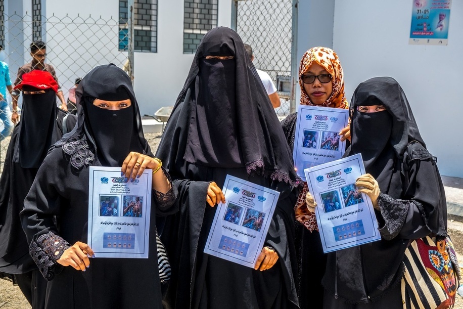 A group of local health workers hold up guidebooks intended for health personnel during WHO's Oral Cholera Vaccination campaign in Aden, Yemen.