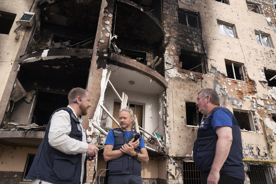 WHO Field Security Daniel Sheeran, WHO Unit Head of Emergency Operations Centre and Incident Manager for Ukraine Ian Clarke and WHO Executive Director of Health Emergencies Programme (HEO) Dr Michael Ryan, in front of damaged residential area, Irpin, Ukraine, 07 May 2022. Title of WHO staff and officials reflects their respective position at the time the photo was taken.