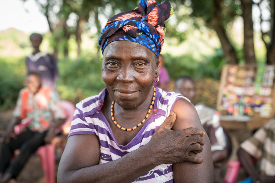 Mabinti received her first COVID-19 vaccine from the mobile vaccination team in Rofunta, Sierra Leone on 6 December 2022.  “Before I was afraid to get the vaccine,” she said. “But now I’ve seen other people getting it, so I’m not afraid. I want to get the vaccine so that I don’t get COVID.”  Rofunta is located in Bombali District and is home to about 690 people. The community of mostly smallholder farming families is eight kilometres of rough dirt road away from the nearest health facility. Most residents in the community do not have the resources to make the journey to the health facility, which means that these mobile outreach campaigns are the only way that most community members are able to get vaccinated against COVID-19.  The vaccination team is made up of a community mobiliser and two nurses from the nearby Yoni Community Health Post. The community mobiliser, Ibrahim Sugar, works with partner organisation GOAL Ireland and speaks the local Temne language. Sugar arrives to the village early to engage with the community members and encourage them to come for their COVID-19 vaccines. The nurses, based at Yoni Community Health Post, take commercial motorbike taxis or walk to get to hard-to-reach communities like Rofunta. In January 2022, WHO, UNICEF and Gavi established the COVID-19 Vaccine Delivery Partnership (CoVDP) to intensify support to COVID-19 vaccine delivery. Working with governments and essential partners, CoVDP provided urgent operational support to the 34 countries that were at or below 10% full vaccination coverage in January 2022 on their pathways toward achieving national and global coverage targets. The greatest benefits of this approach were increases in full vaccination and booster coverage for in both general and high-priority populations – older adults, healthcare workers, and persons with co-morbidities, including immunocompromised persons. Read more about the https://www.who.int/emergencies/diseases/novel-coronavirus-2019/covid-19-vaccines/covid-19-vaccine-delivery-partnership . - Photo produced in collaboration with UNICEF