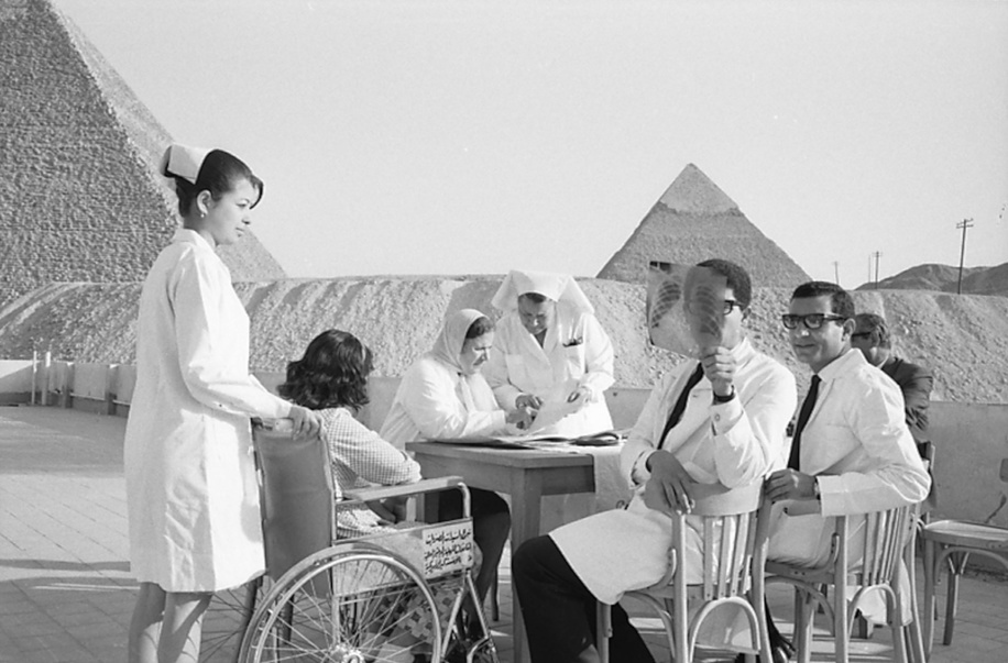 The incidence of heart and joint disabilities resulting from rheumatic fever was indeed high in the United Arab Republic, especially among the poorer classes. This was particularly true in those regions where population density and overcrowding encourage the spread of streptococcal infection. On the terrace of the hospital. At the table in the background, Dr Zahira Abdine, Directress of the clinic, examines the file of a young patient.