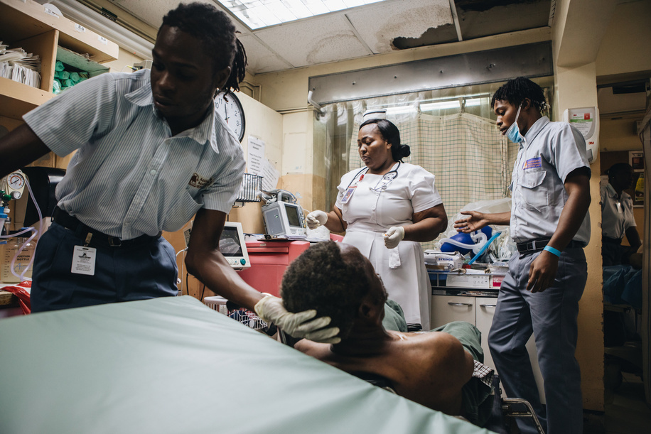 2020 Year of the Nurse and Midwife.

Porters move an unconscious patient onto a stretcher as Trecia Simone Stewart, 41, a certified emergency nurse prepares for the patient's intake at Spanish Town Hospital.

-
Read the story: <a target='_blank' href='https://www.who.int/news-room/feature-stories/detail/emergency-nursing-in-jamaica'>https://www.who.int/news-room/feature-stories/detail/emergency-nursing-in-jamaica</a>