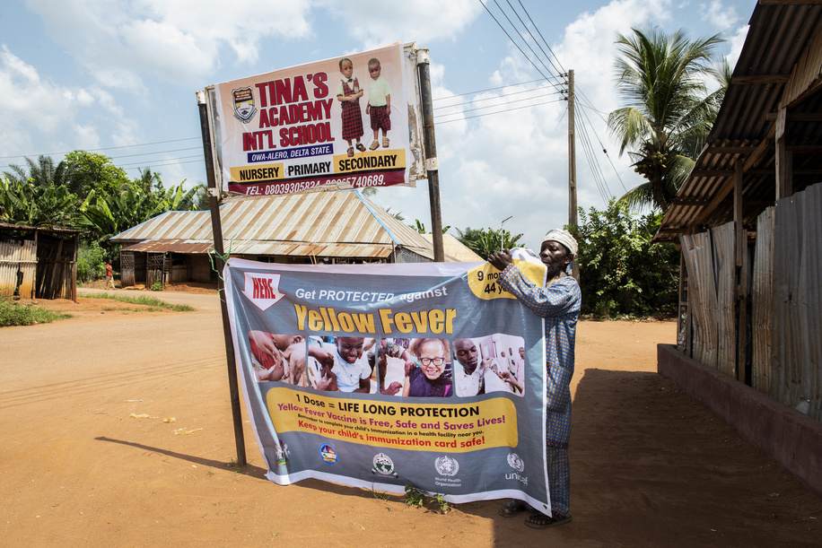 Daniel Eborka, a school employee, holds a banner promoting the yellow fever vaccination campaign at Tina's Academy International School. A team of vaccinators were dispatched by the government in and around Owa-Alero, which has been one of the places with a high number of yellow fever cases. The World Health Organization (WHO) is supporting the Nigeria Centre for Disease Control and health authorities in the states of Delta and Enugu to respond to an outbreak of yellow fever that was confirmed in early November 2020. WHO and partners are assisting with case investigation, case management and community engagement, among other activities. In addition, in response to this outbreak a planned yellow fever vaccination campaign in Delta was brought forward, starting on 10 November. Nigeria had been reporting suspected cases of the yellow fever in all 36 states and the federal capital territory since its outbreak in September 2017 and is one of the countries implementing the global eliminate yellow fever epidemics (EYE) strategy. As part of the strategy, Nigeria has developed a 10-year strategic plan for the elimination of yellow fever epidemics. Through this strategy, the country plans to vaccinate at least 80% of the target population in all states by 2026. For more information on yellow fever: https://www.who.int/health-topics/yellow-fever