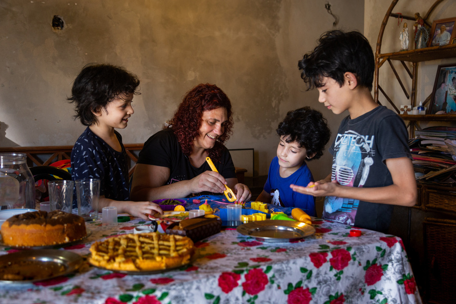 Gabriel, 7, and his mother, Karina, play with his brothers at their home in Moreno, Argentina, on Dec. 10, 2020. Since the family is together for long periods of time due to the COVID-19 pandemic, they usually all participate in the activities to engage Gabriel. One of the goals of CST is to help families involve their children more often in everyday activities. These are great opportunities for children to learn. The Caregiver Skills Training (CST) programme was developed by WHO and is being implemented in Argentina by international partner Programa Argentino para Niños, Adolescentes y Adultos con Condiciones del Espectro Autista (PANAACEA) to serve families of children with developmental delays and disabilities. The programme uses a family-oriented approach and is designed to be delivered by trained non-specialists (community-based workers, peer caregivers or others) as part of a network of health and social services for children and their families. CST consists of nine group sessions and three individual home visits, focused on training caregivers how to use everyday play and home activities and routines as opportunities for learning and development. The sessions specifically address communication, engagement, daily living skills, challenging behaviour and caregiver coping strategies. Gabriel was diagnosed with autism at age 3. He was not speaking and did not interact with other people, including his family. As a mother of four, Karina Visciglia struggled to care for her family and find Gabriel the services he needed. Through CST facilitators and PANAACEA, Karina gained access to a network of services and a support system. She saw significant improvements in her ability to connect and communicate with her son, and did so through the use of play activities, games, and home routines. She also says she felt empowered and improved herself by taking part in the group sessions. In general, caregivers of children with developmental delays often experience very high levels of distress and, in many cases, interruptions or discontinuation of care services. The COVID-19 pandemic has had major impacts on mental health but particularly on that of women and those taking care of young children with developmental disabilities. The CST programme was adapted to a remote, online version so that it was able to continue during the pandemic in Argentina.