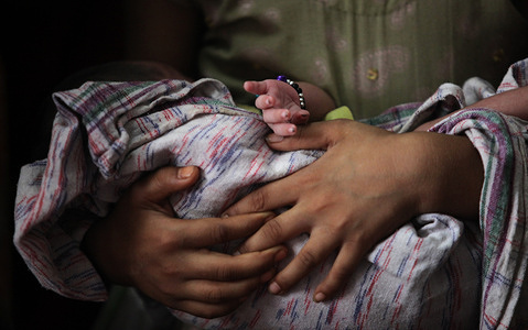 Illustration of Immunization in India A women holds her baby before a routine vaccination at an immunization site, in Ghaziabad, Uttar Pradesh India