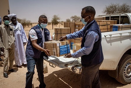 North Darfur, Sudan - 25 April 2022: Head of WHO’s North Darfur Sub-Office Dr Abdelrahman Sharif (right) and WHO Community Systems Strengthening Officer Ezzedin Adam Mohamad Adam (left) deliver supplies to a new health care centre in the village of Abu Gaw. Prior to its construction, people from Abu Gaw had to travel long distances to reach health services, but many couldn’t afford the cost of transport. Their previous health care centre was destroyed and residents of Abu Gaw fled from their village during the war in Darfur in 2004. Since 2018, about 8000 people have returned to the village from displacement camps. The community identified rebuilding the health centre as a priority through a series of community health dialogues facilitated by the WHO with North Darfur health authorities. Community dialogues empower disadvantaged populations to take an active role deciding on their health priorities, proposing solutions for their health needs, and holding local health authorities accountable. The dialogues in Abu Gaw provided guidance for the community about how and where to advocate for the health services they needed most. Community leaders identified a local nongovernmental organization, Africa Humanitarian Action (AHA) to build the facility. UNHCR supported the project with funding from the government of Denmark. The Ministry of Health is overseeing the operation and staffing of the health centre, and WHO is providing equipment, medicines and staff training. Sudan is one of the 115 countries and areas supported by the Universal Health Coverage Partnership, WHO’s largest platform for international cooperation on delivering universal health coverage through a primary health care approach. Primary health care-oriented health systems maximize the quality of the health system, while also enhancing equity and solidarity, thus improving social cohesion. With 2.5 million internally displaced people (IDPs) in Sudan, there is an urgent need to strengthen basic services and build community resilience so that people can return home and live in peace. - Title of WHO staff and officials reflects their respective position at the time the photo was taken.