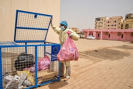 Khartoum, Sudan - 20 April 2022: Hussein S. H. disposes of medical waste in a locked bin outside the Omar Ibn Khatab Primary Health Centre. In collaboration with European Civil Protection and Humanitarian Aid Operations (ECHO), WHO has supported 105 primary health care centres in Khartoum, including this one, to upgrade infection prevention and control (IPC) measures as part of the COVID-19 response. The support included providing personal protective equipment (PPE), installing signage showing safety measures, creating a triage/screening system at health facility entrances, installing additional hand washing stations, supporting safe waste management and providing staff training. These measures have helped protect health workers and ensured service provision throughout the pandemic, and will serve to strengthen the health system beyond COVID-19. ECHO has also provided support for COVID-19 rapid response teams, isolation centres and laboratories in Khartoum.