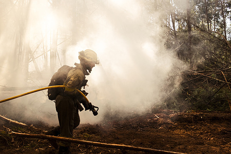Arbo, Pontevedra, Spain: A firefighter works to extinguish a wildfire in the forest near Arbo on 3 August 2022. The fire burned at least 400 hectares of land along the border between Spain and Portugal.  Climate change makes it more likely for droughts and wildfires to happen. Wildfires can cause death and injury from suffocation, burns and smoke inhalation. They can also cause respiratory and cardiovascular problems from smoke and ashes, negatively impact mental health, disrupt health services and lead to loss of housing and livelihoods. Read more about https://www.who.int/news-room/fact-sheets/detail/climate-change-and-health