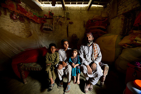 Momin (right) and his family in their home in the village of Mingora in Pakistan's Swat valley. Their home was submerged in the floods a week before this photograph was taken. The water burst through an opening in the ceiling. Catastrophic floods in Pakistan in August 2022 killed some 1,400 people, destroyed more than half a million homes and displaced over 660,000 people into camps. Many more people are displaced in host communities. More than 750,000 livestock – a critical source of income for many families – died after the rainfall, which in August was more than five times the national 30-year average in some parts of Pakistan. According to the Food and Agriculture Organization, the floods damaged 1.2 million hectares of agricultural land in Sindh Province alone. Some 33 million people have been affected, and access to many vulnerable communities was cut off as hundreds of bridges and thousands of kilometres of roads were destroyed or washed away.  WHO is supporting the Government of Pakistan to respond by delivering supplies needed by health facilities and increasing disease monitoring to prevent the spread of infectious diseases. https://www.who.int/emergencies/situations/pakistan-crisis