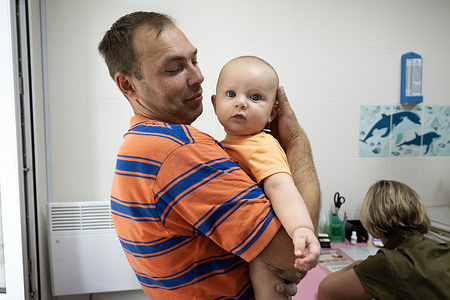 Artem is held by his father before he is vaccinated at the Brovary City Centre of Primary Medical and Sanitary Aid on 25 July 2023. Today, Artem receives his third vaccination. Artem's parents carefully adhere to the vaccination schedule, so that their son grows up healthy and protected from infections.