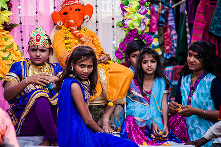 Shivaratri Festival in Pushkar, India. Young girls sitting together with a person wearing an elephant mask during celebrations of the Shivaratri Festival in the city of Pushkar. The elephant mask represents Ganesha, a deity in the Hindu pantheon.