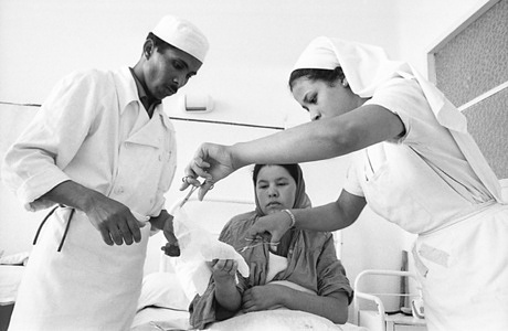 While modern treatment was available in the 3 or 4 major hospital centres of Morocco in 1957 there was almost no national staff to run the general health service. Contact between WHO and the health problems of Morocco started some four years before independence when it was realized that independence in the medical field meant a greatly intensified training programme.  Also, it was not sufficient to calculate the output of trainees needed to run the medical services of the day; output had to be geared to new targets set by the Government’s five-year plan for social and economic development (one health centre for every 45,000 inhabitants and one dispensary for every 15,000 inhabitants). To provide the personnel necessary for this service not only was a 100$ increase in output of higher trained staff necessary it also became essential to create a new grade of trained basic personnel. Thus the “aides sanitaires” came into being.  With WHO and UNICEF help, under the prosaic symbol “Morocco” twenty-six schools for “aides sanitaires” were created.1964 will see 1,000 of these aides qualify, bringing to 4335 the cumulative number of these key workers who have been trained since 1957. On qualification “aides sanitaires” are assigned to rural health centres. Each rural health centre had a full-time doctor helped by two nurses and five aides sanitaires, of whom three are itinerant, doing nothing but home visiting.   In these photos WHO photographer, Jean Mohr, shows something of the 2-year training given to aides sanitaires through 5 trainees between the ages of 24 and 29, 2 of them being young women. Yahia Hilal BOUZIANI, 24, is the second of five children of a poor farmer. He, however, prefers to work in town rather than in the country. He is unmarried and lives in a dormitory at the hospital. He is a second-year student but thinks that the studies are very difficult and tiring. He would like to specialize in anesthesiology after the two-year course. Bouziani is doing part of his training in the surgical section of Hospital Avissen. His main job is to change bandages.