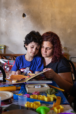 Karina and her son Gabriel, 7, read a book together at their home in Moreno, Argentina, on Dec.10, 2020. Karina spends a lot of time engaging with Gabriel through activities such as reading, which can promote communication, a practice learned in the CST programme. The Caregiver Skills Training (CST) programme was developed by WHO and is being implemented in Argentina by international partner Programa Argentino para Niños, Adolescentes y Adultos con Condiciones del Espectro Autista (PANAACEA) to serve families of children with developmental delays and disabilities. The programme uses a family-oriented approach and is designed to be delivered by trained non-specialists (community-based workers, peer caregivers or others) as part of a network of health and social services for children and their families. CST consists of nine group sessions and three individual home visits, focused on training caregivers how to use everyday play and home activities and routines as opportunities for learning and development. The sessions specifically address communication, engagement, daily living skills, challenging behaviour and caregiver coping strategies. Gabriel was diagnosed with autism at age 3. He was not speaking and did not interact with other people, including his family. As a mother of four, Karina Visciglia struggled to care for her family and find Gabriel the services he needed. Through CST facilitators and PANAACEA, Karina gained access to a network of services and a support system. She saw significant improvements in her ability to connect and communicate with her son, and did so through the use of play activities, games, and home routines. She also says she felt empowered and improved herself by taking part in the group sessions. In general, caregivers of children with developmental delays often experience very high levels of distress and, in many cases, interruptions or discontinuation of care services. The COVID-19 pandemic has had major impacts on mental health but particularly on that of women and those taking care of young children with developmental disabilities. The CST programme was adapted to a remote, online version so that it was able to continue during the pandemic in Argentina.