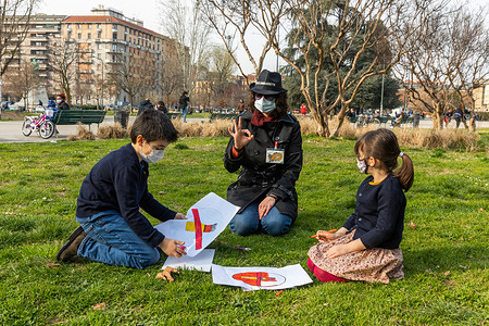 Guido (L) and Livia (R) participate in an anti-tobacco workshop called "Agent 00 Cigarettes, LILT Mission," with volunteer Alice (Center). The workshop is part of a campaign by LILT (Italian League For The Fight Against Cancer) to educate kids about the dangers of smoking and encourage them to make healthy, tobacco-free life choices on 9 March 2021 in Milan, Italy. Milan is “going green” to fight against climate change and improve the quality of life of its 1.4 million citizens. In the last few years, the local government announced plans to plant 3 million trees by 2030. This will increase greenery in the city but will also have a positive effect on the quality of air, and consequently on the health of the people. The city’s increase in trees, about a 30% expansion, could absorb 5 million tons of carbon dioxide every year, while reducing fine particles linked to respiratory diseases and cancer by 3,000 tons in the next ten years. Likewise, efforts to support a low-carbon, sustainable recovery from the COVID-19 crisis led to the city announcing hundreds of miles of new bike lanes and sustainable green spaces in the city. These spaces encourage both children and adults to move, whether it’s through playing or active transport, like biking and walking. Physical activity is good for hearts, minds and bodies - preventing and managing heart disease, cancer and diabetes. Milan’s move to incorporate more greenery in its urban development is most noticeable in the now famous ‘Vertical Forest’- two residential tower blocks built in 2014 that feature 800 trees, 15,000 plants and 4,500 shrubs covering every balcony. In 2021 Milan introduced one of the most comprehensive plans to create a smoke free city in Italy. The city's public parks, dog areas, cemeteries, playgrounds, children's sports and recreational areas, stadiums and public transport stops are all now smoke-free spaces, improving the air we breath and decreasing diseases caused by tobacco. WHO supports cities to prevent disease, promote road safety and protect the environment. Cities like Melbourne, Rio de Janeiro, Shenzhen, Bengaluru and Amman have committed to decreasing tobacco use through smoke-free public spaces, banning tobacco advertising and raising tobacco taxes. Milan’s regulation supports the global noncommunicable diseases action plan to reduce global prevalence of tobacco use by 30% by 2025. With this in mind, educational programs sponsored by the Italian League for the Fight against Cancer of Milan provide training of “Special Agents 00 Cigarettes” to young people who undertake not to start smoking and to adopt a healthy lifestyle with healthy eating, physical activity, and balanced well-being. The program aims to join efforts of teachers, institutions and families, to sensitize students to “a school and a smoke-free future” and, more generally, to a conscious and healthy lifestyle. It starts in the fourth classes, with the intervention of educators, and continues in the fifth classes.